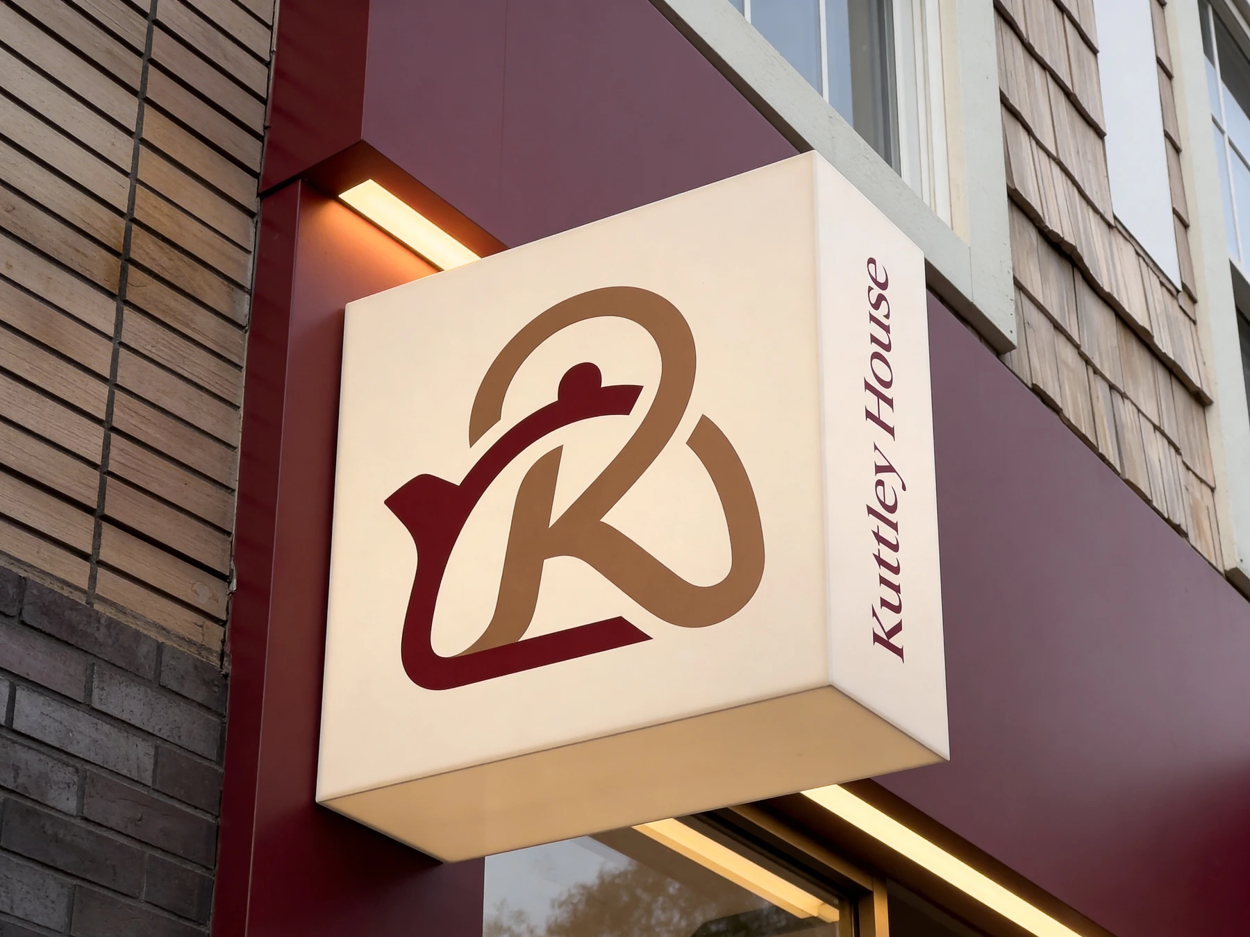 The illuminated Kuttley House sign with its two-color logo outside the café